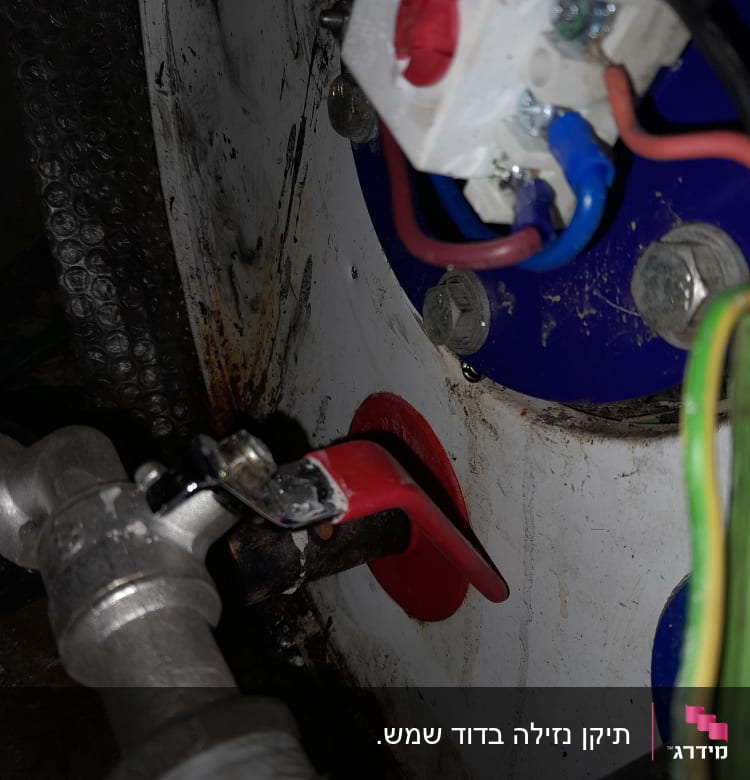 שסתום מתכת עם ידית אדומה וצינורות מחוברים